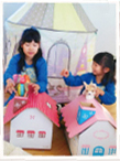 二人の女の子がおうち型収納ボックスの赤とピンクを並べ、楽しそうに遊んでいる写真